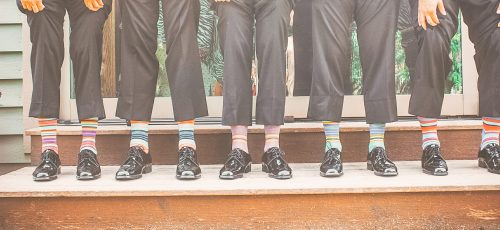 five-men-wearing-colourful-socks-holding-their-pant-legs-up